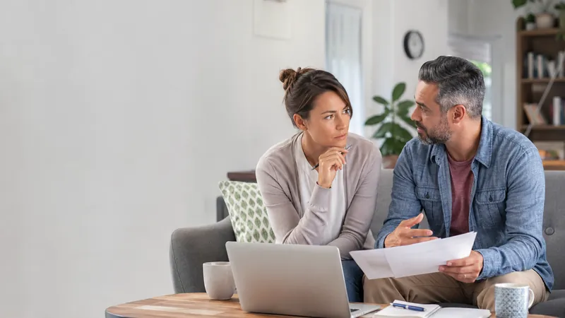 American Income Life insurance guide - Mallard Mortgage Protection Couple sitting at home reviewing insurance paperwork on a laptop